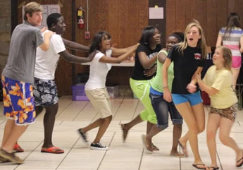 Group of kids in a line with their hands on the person in front's sholders