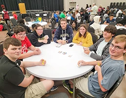 Group of kids sitting around a table in a conference hall